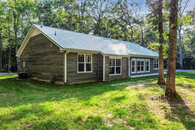 rear view of house featuring central air condition unit and a lawn