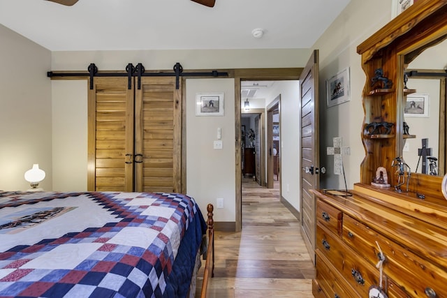 bedroom featuring ceiling fan, hardwood / wood-style floors, a closet, and a barn door