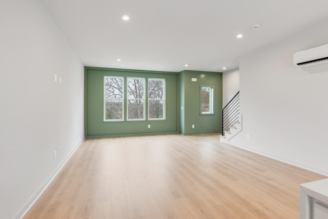 unfurnished living room with a wall mounted AC and light hardwood / wood-style flooring