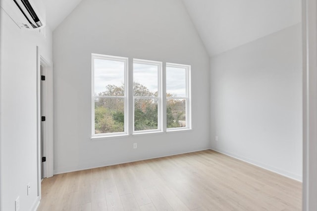 interior space with high vaulted ceiling, a wall mounted AC, and light hardwood / wood-style floors