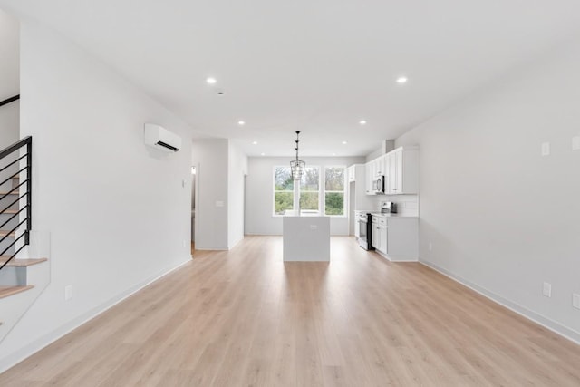 unfurnished living room featuring a wall mounted AC and light hardwood / wood-style floors