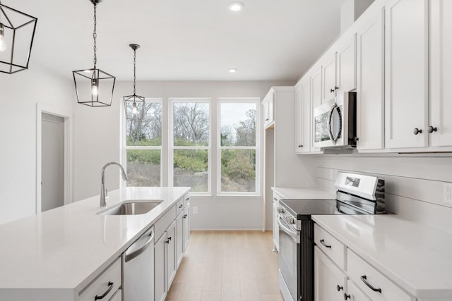 kitchen with stainless steel appliances, white cabinetry, an island with sink, and sink