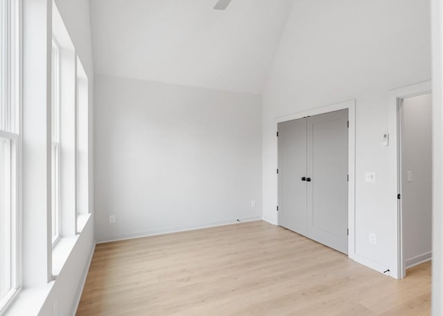 unfurnished bedroom with high vaulted ceiling, a closet, ceiling fan, and light hardwood / wood-style flooring