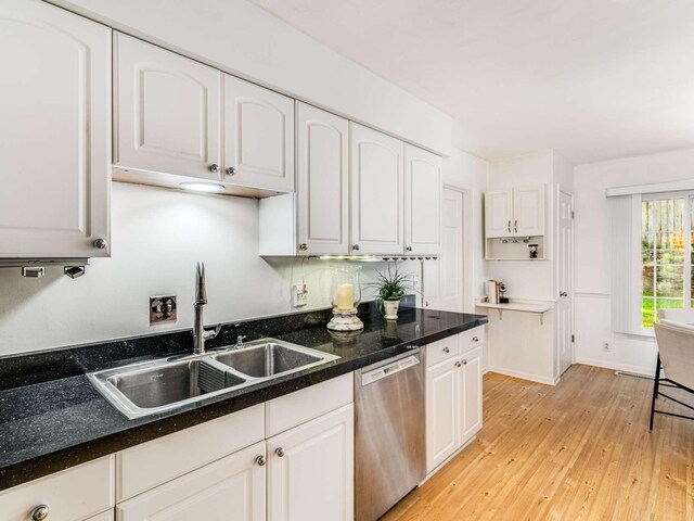 kitchen featuring stainless steel dishwasher, white cabinetry, sink, and light hardwood / wood-style flooring