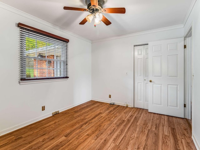 unfurnished bedroom featuring wood-type flooring, a closet, ceiling fan, and crown molding