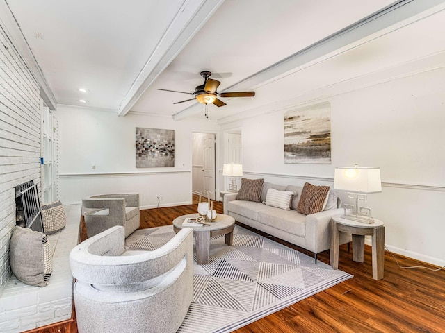 living room featuring hardwood / wood-style floors, ceiling fan, ornamental molding, a fireplace, and beam ceiling