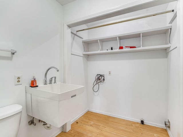 laundry area featuring sink and hardwood / wood-style flooring