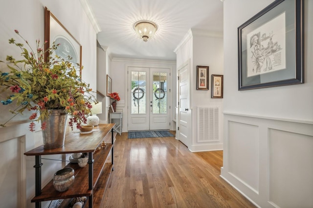 foyer with french doors, hardwood / wood-style floors, and crown molding