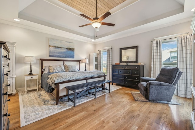 bedroom with ceiling fan, crown molding, light hardwood / wood-style floors, and a raised ceiling