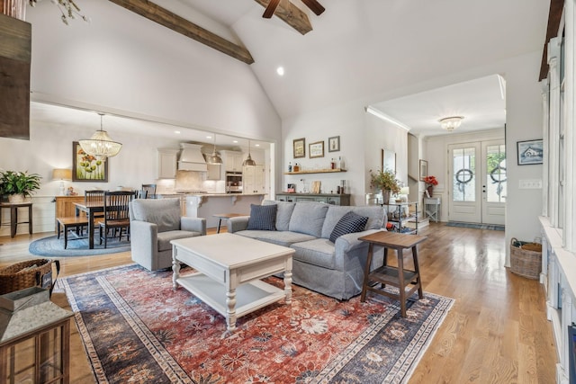 living room featuring a notable chandelier, french doors, light hardwood / wood-style floors, high vaulted ceiling, and beam ceiling