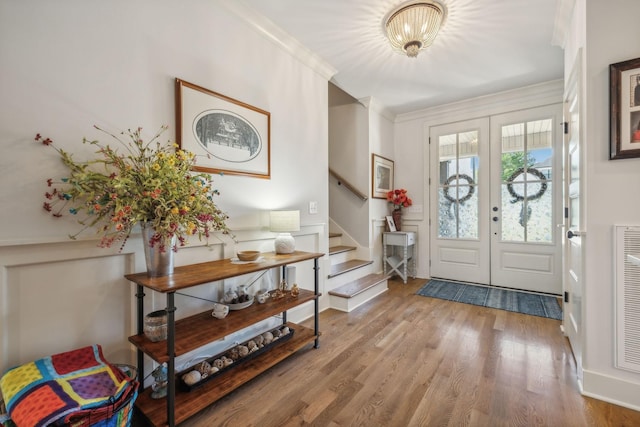 entryway with french doors, crown molding, and hardwood / wood-style floors