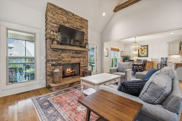 living room with hardwood / wood-style floors, a chandelier, high vaulted ceiling, a fireplace, and beam ceiling