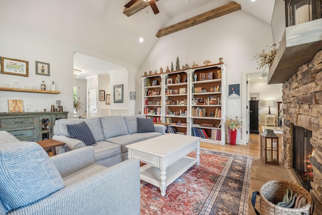 living room featuring beam ceiling, ceiling fan, a stone fireplace, and high vaulted ceiling