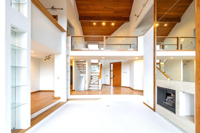 unfurnished living room with a towering ceiling, beamed ceiling, and wooden ceiling