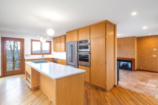 kitchen with stainless steel appliances, sink, a center island, light hardwood / wood-style flooring, and pendant lighting