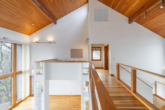 hall with wood ceiling, a wealth of natural light, and beamed ceiling