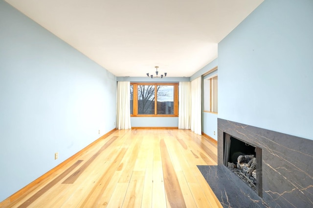 unfurnished living room featuring a notable chandelier, hardwood / wood-style floors, and a fireplace