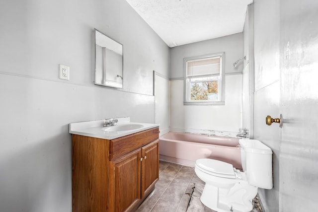 bathroom featuring tile patterned flooring, toilet, vanity, a bathing tub, and a textured ceiling