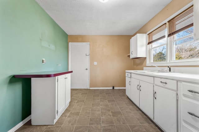 kitchen featuring sink, white cabinets, and a textured ceiling