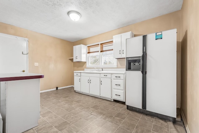 kitchen with white refrigerator with ice dispenser, white cabinets, a textured ceiling, and sink