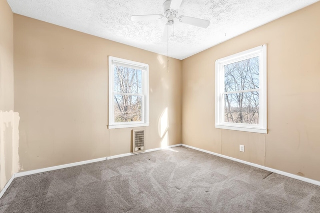 carpeted empty room featuring a textured ceiling, ceiling fan, and heating unit