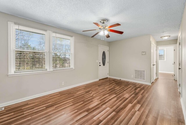 empty room with a textured ceiling, ceiling fan, and hardwood / wood-style floors