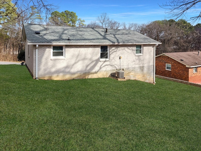 back of property featuring central air condition unit and a lawn