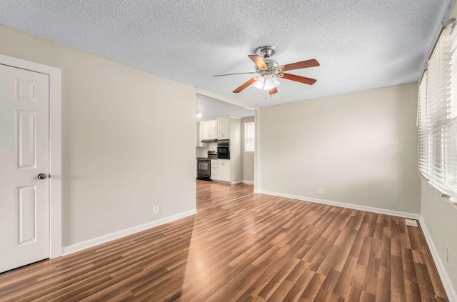 spare room with a textured ceiling, ceiling fan, and dark hardwood / wood-style flooring