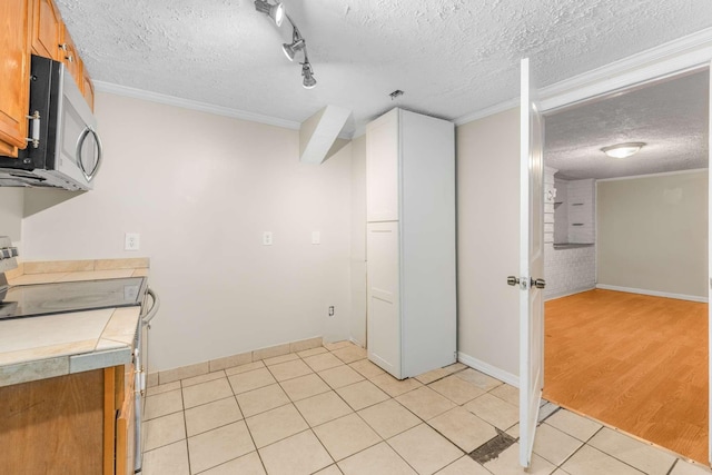 kitchen featuring stainless steel appliances, a textured ceiling, light tile patterned floors, and crown molding