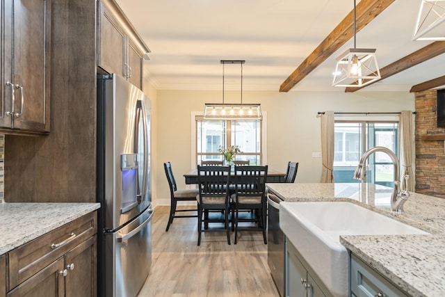 kitchen featuring sink, stainless steel appliances, light stone countertops, and pendant lighting