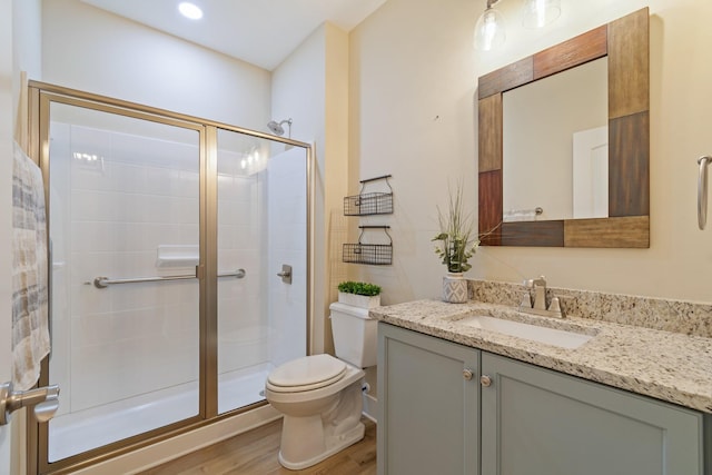 bathroom featuring toilet, a shower with door, vanity, and hardwood / wood-style floors