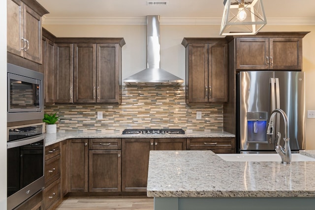 kitchen featuring stainless steel appliances, light stone countertops, wall chimney range hood, and decorative backsplash