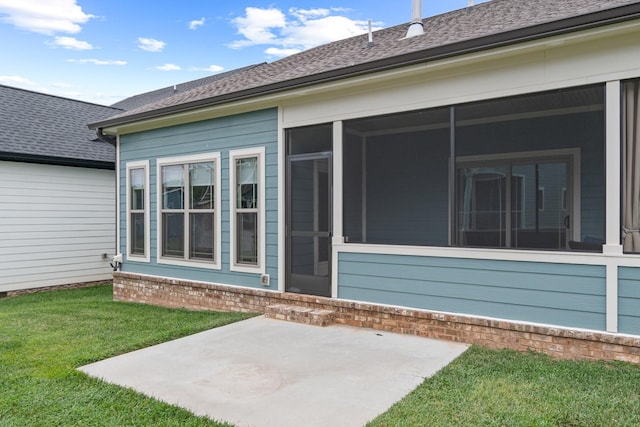 view of exterior entry featuring a lawn and a patio area