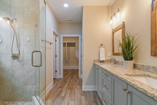 bathroom with wood-type flooring, vanity, and a shower with shower door