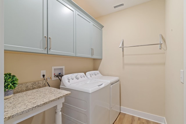 laundry area with light hardwood / wood-style flooring, cabinets, and washing machine and dryer