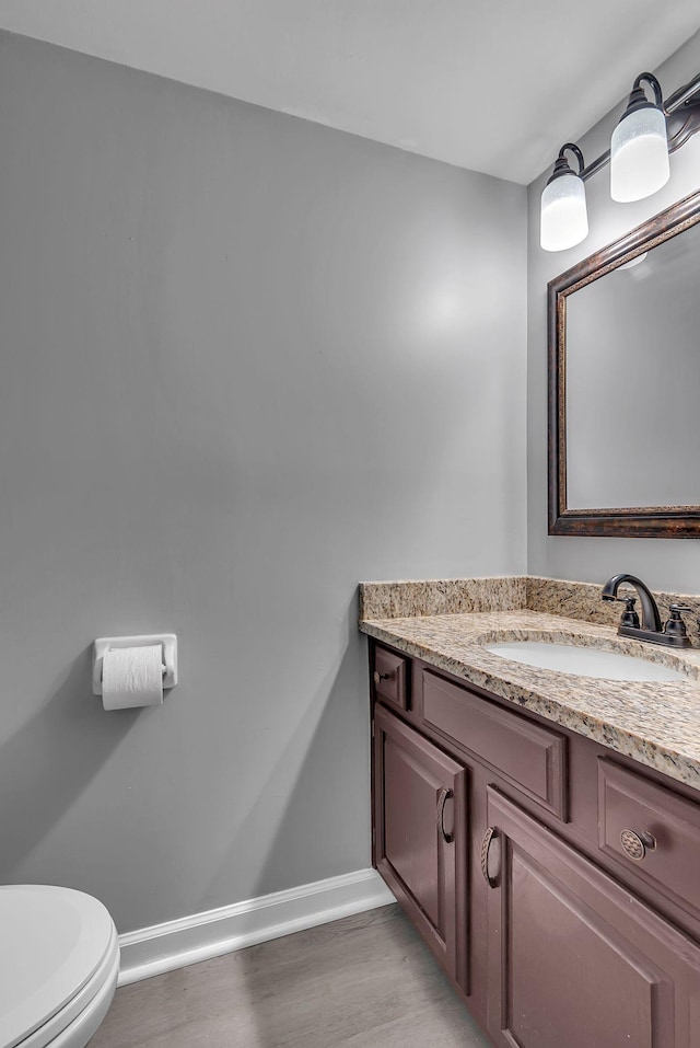 bathroom with toilet, vanity, and hardwood / wood-style floors