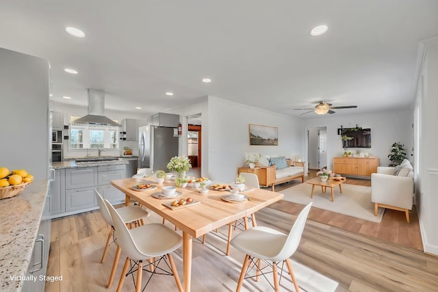 dining space with ceiling fan, light wood-type flooring, and sink