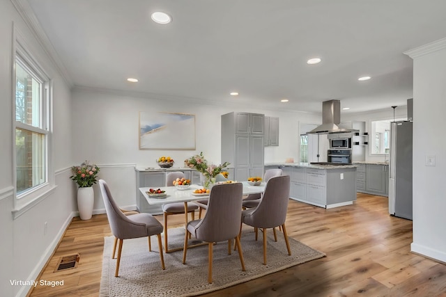 dining area featuring light wood-type flooring and ornamental molding