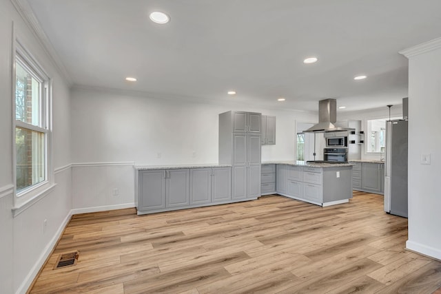 kitchen featuring island range hood, gray cabinetry, stainless steel appliances, crown molding, and kitchen peninsula