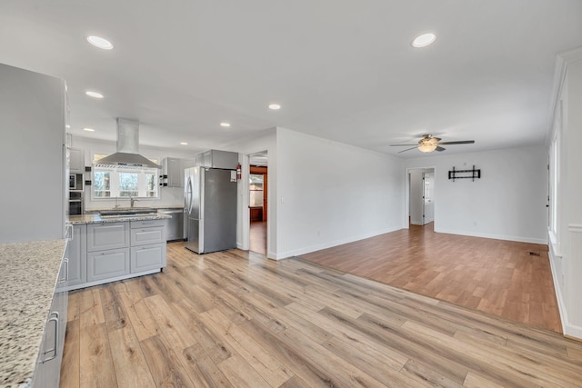 kitchen with light stone counters, ceiling fan, light hardwood / wood-style flooring, stainless steel fridge, and island range hood