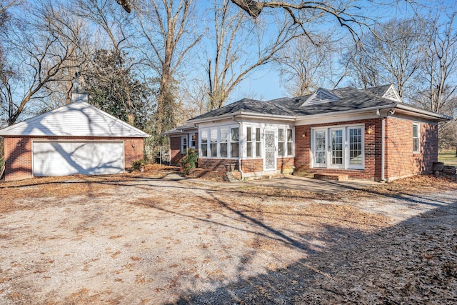 view of front of home with a sunroom, a garage, and an outbuilding