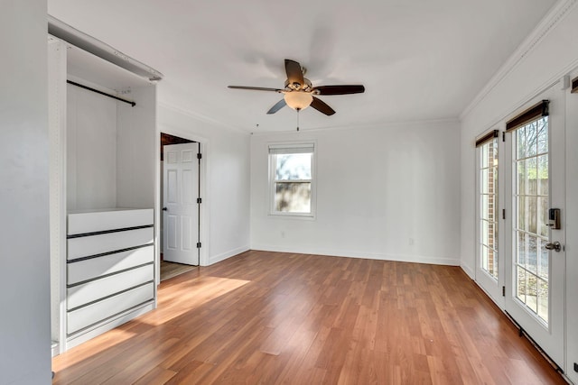 unfurnished bedroom featuring ceiling fan, crown molding, light hardwood / wood-style flooring, and multiple windows