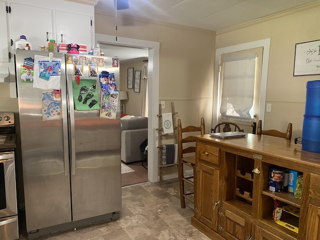 kitchen with stainless steel fridge, white cabinetry, and crown molding