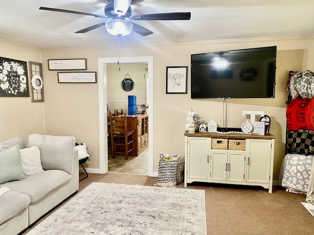 living room featuring ceiling fan, crown molding, and light colored carpet