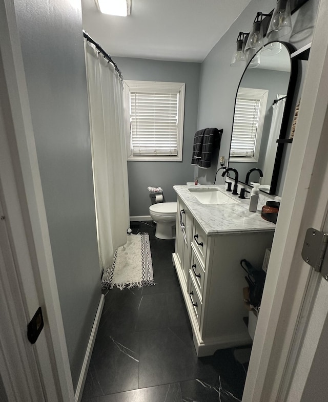 bathroom featuring toilet, vanity, and plenty of natural light