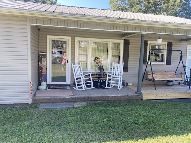 entrance to property with a porch and a yard