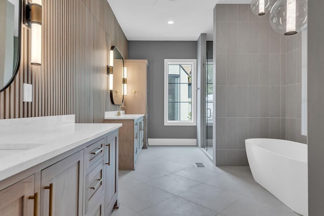 bathroom with tile walls, tile patterned flooring, plus walk in shower, and vanity