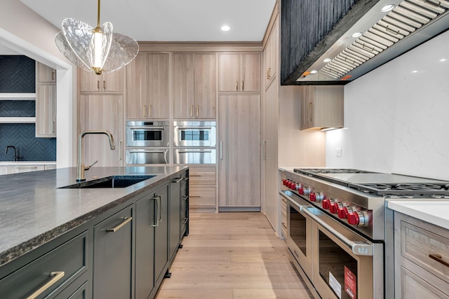 kitchen with stainless steel appliances, sink, light brown cabinets, hanging light fixtures, and premium range hood