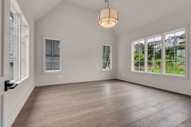 spare room with light wood-type flooring and vaulted ceiling