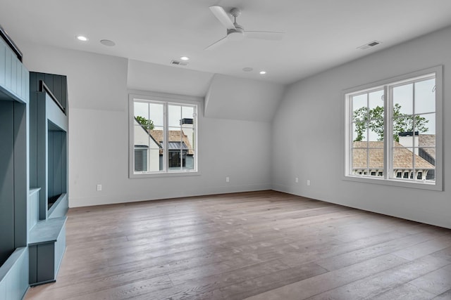 unfurnished living room featuring lofted ceiling, light wood-type flooring, ceiling fan, and plenty of natural light